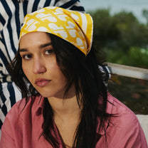 Femme portant sur la tête un foulard en soie imprimé jaune et blanc