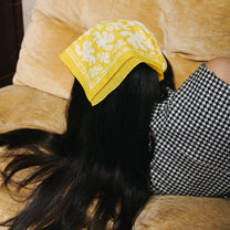 Femme portant sur la tête un foulard en coton jaune et blanc