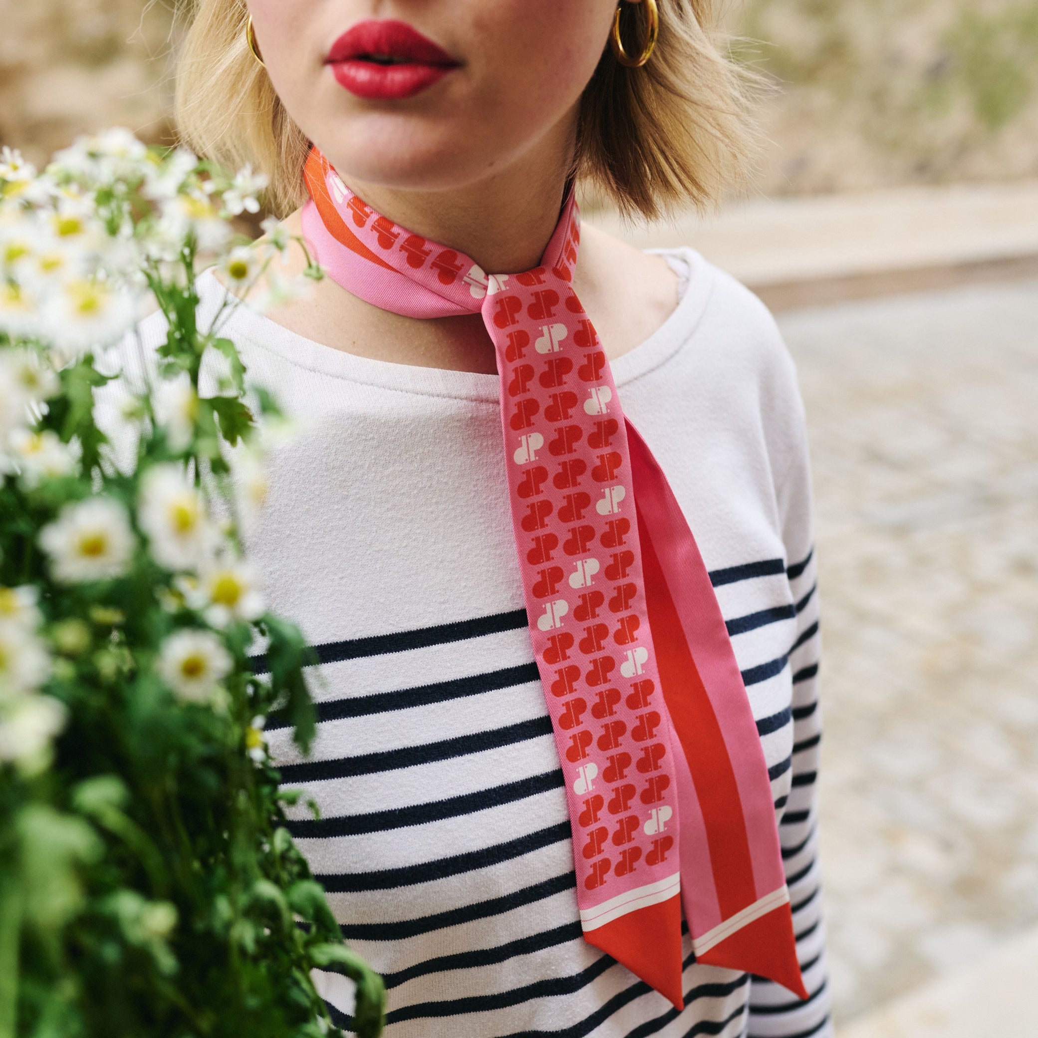 Femme portant autour du cou un foulard imprimé rose rouge et blanc