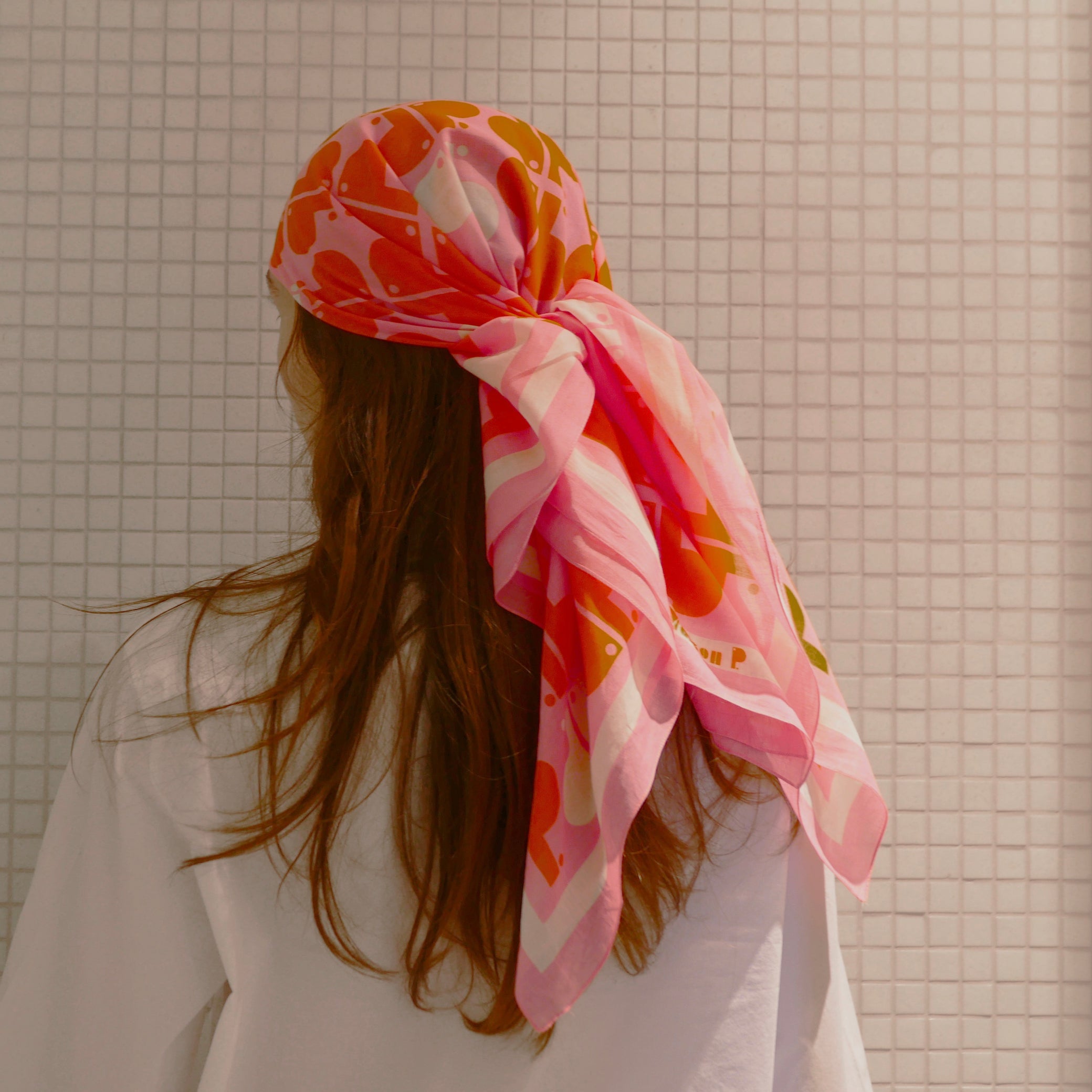 Femme portant sur la tête un foulard en coton imprimé rose rouge et blanc